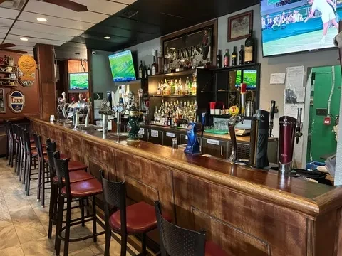 Empty casual bar with wooden counter, beer taps, and sports TVs.