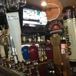 Close-up of bar with beer taps, sports TV, and orange slice decor.
