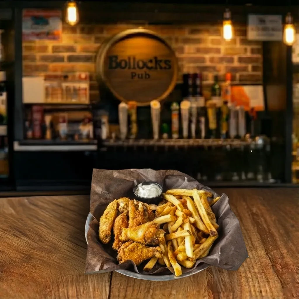 Crispy chicken wings, fries, and dipping sauce on a pub table.