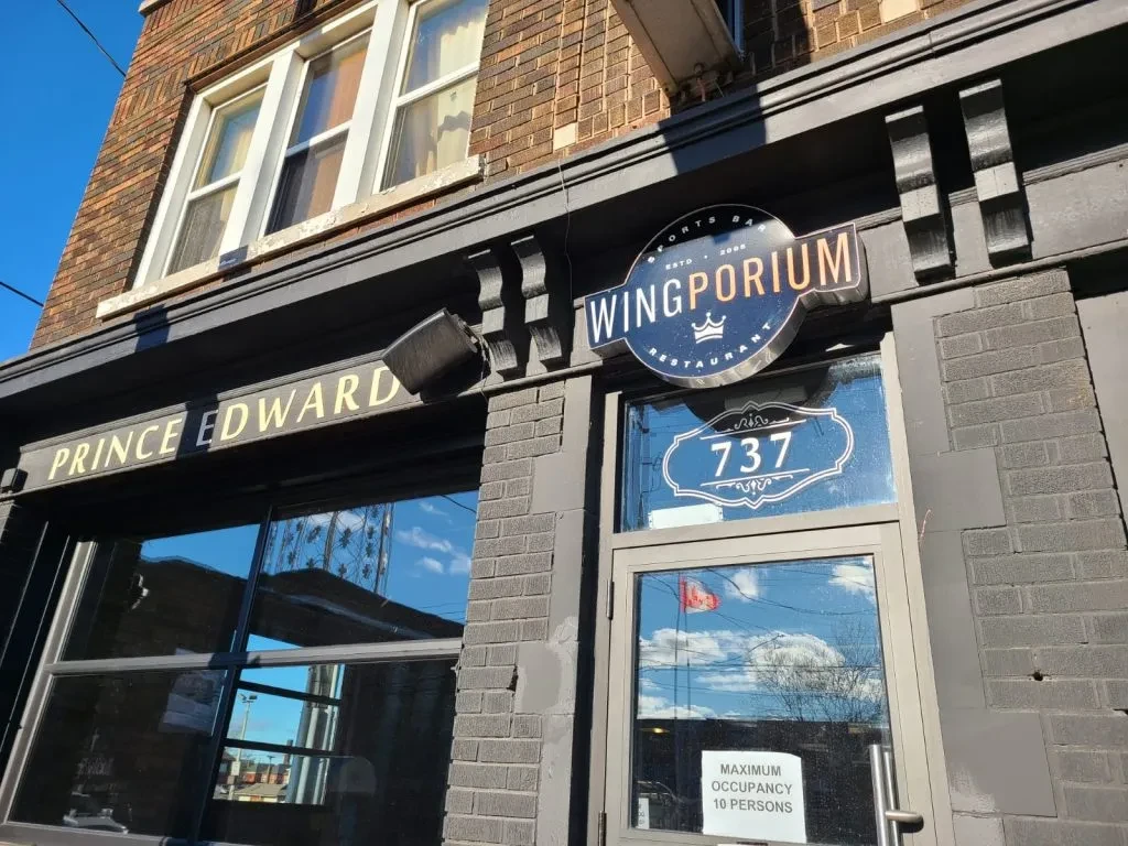 Wingporium Sports Bar exterior with Prince Edward sign, reflecting blue sky.