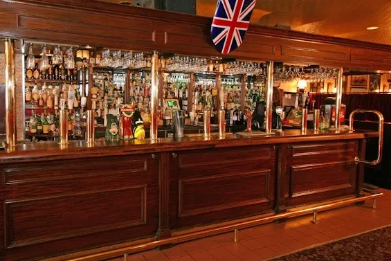 Traditional British pub interior with dark wood, brass taps, and a Union Jack.