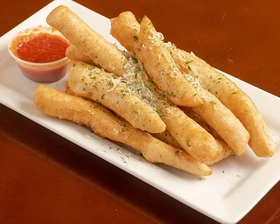 Plate of golden-brown breadsticks with cheese, herbs, and marinara dip.