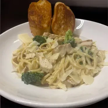 Close-up of creamy chicken pasta with broccoli, Parmesan, and toasted bread.