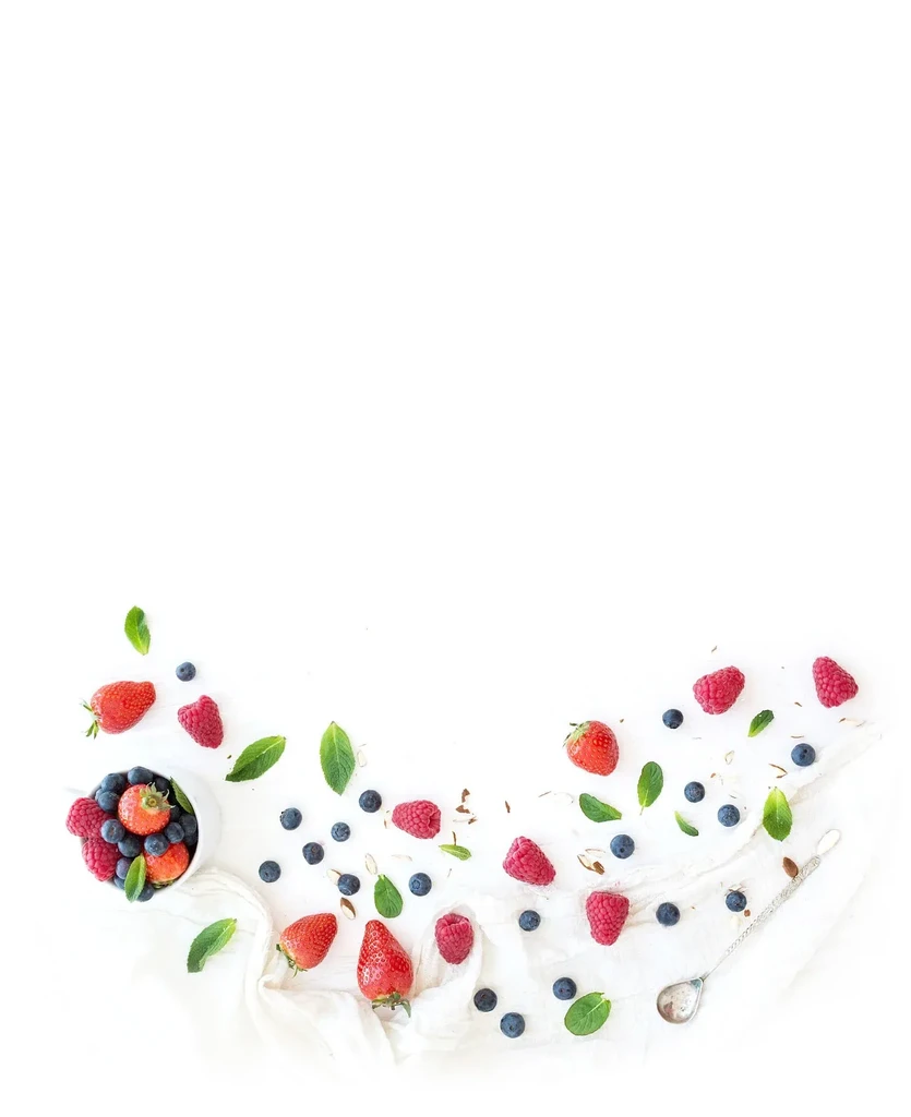 Flat lay of mixed fresh berries, mint, and a silver spoon.