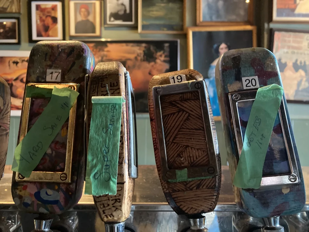 Four unique beer tap handles show names and numbers.