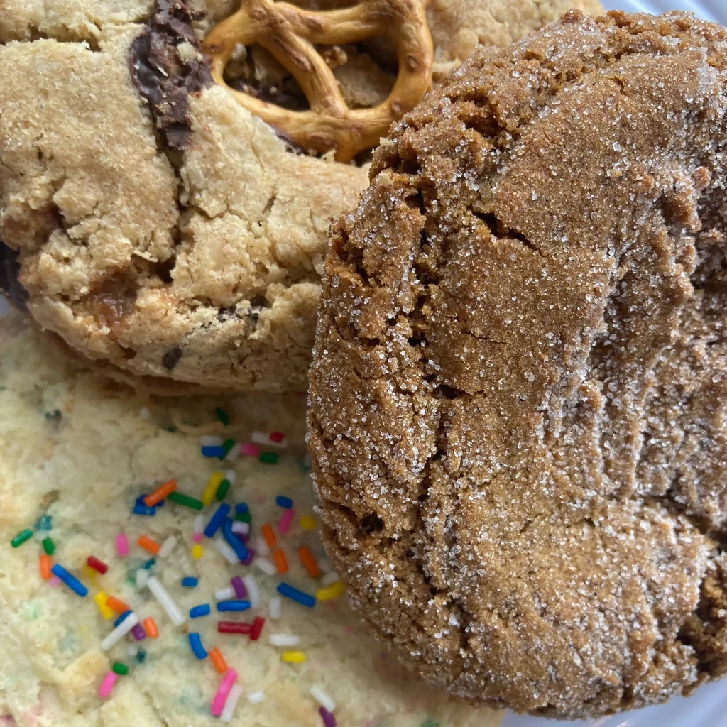 Close-up of three distinct cookies: pretzel, sugar-coated, and sprinkle.