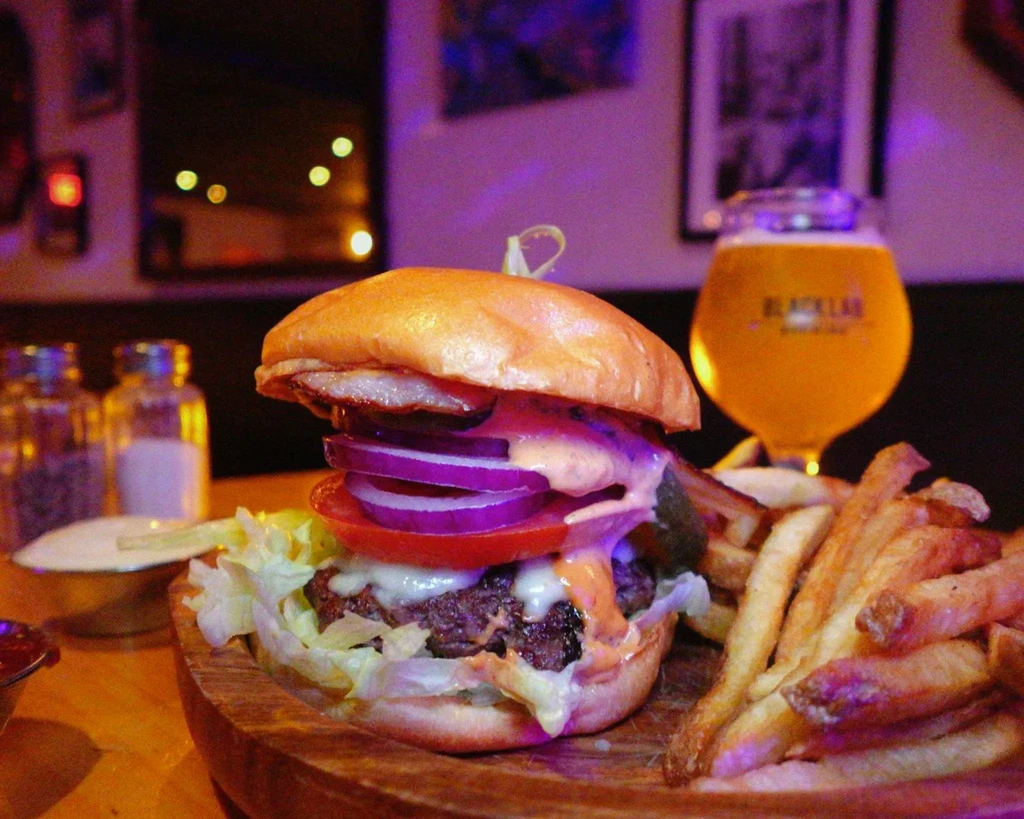 Gourmet burger, fries, and a Black Lab beer on a wooden board.