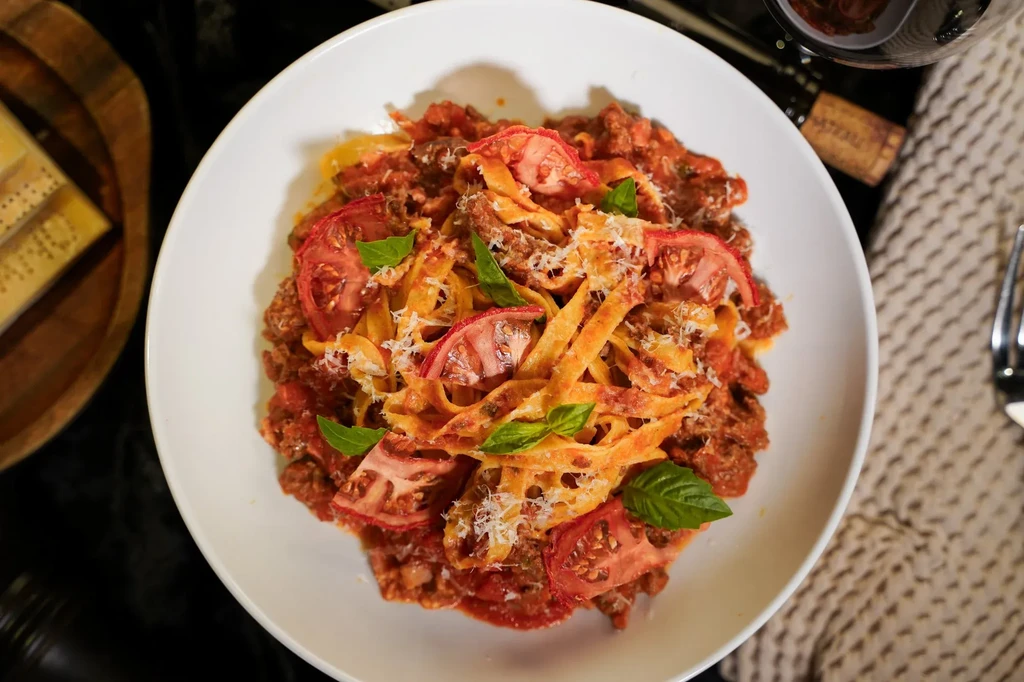 Overhead shot of pasta with meat sauce, tomato, basil, and cheese.