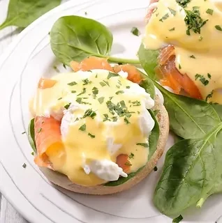 Two servings of Eggs Benedict with smoked salmon, spinach, Hollandaise.