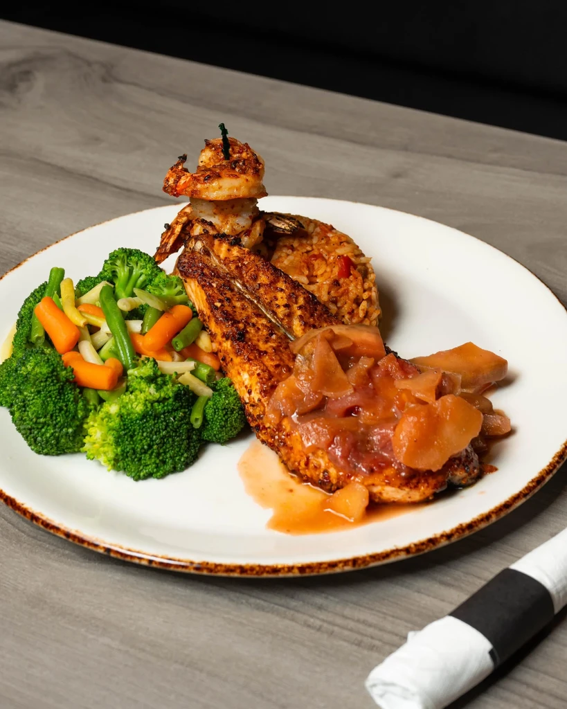 Grilled fish or chicken topped with shrimp, relish, rice, and vegetables.