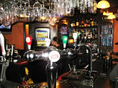 Well-stocked bar interior with beer taps, liquor bottles, and a bartender.