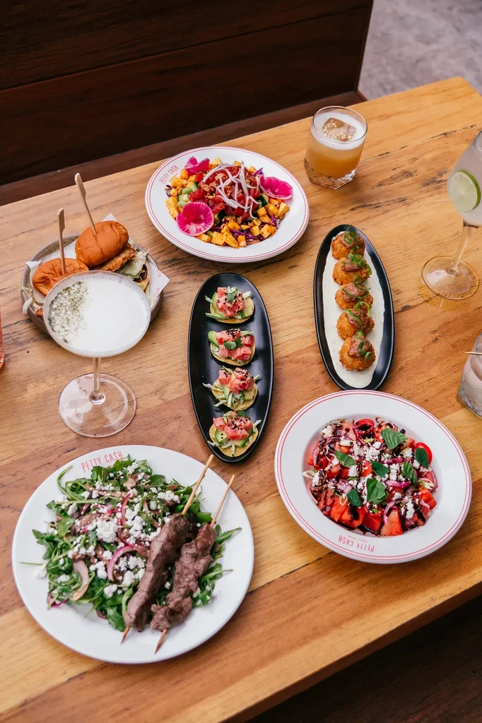 A wooden dining table laden with diverse food and colorful cocktails.