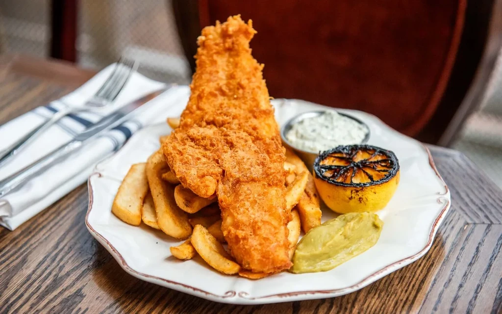 Crispy fish and chips with tartar sauce, grilled lemon, green puree.
