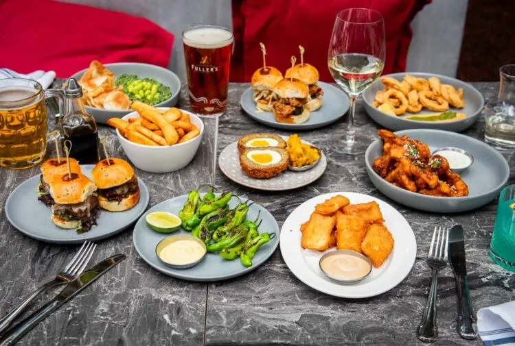 A table full of appetizers, beer, wine, and cocktails.