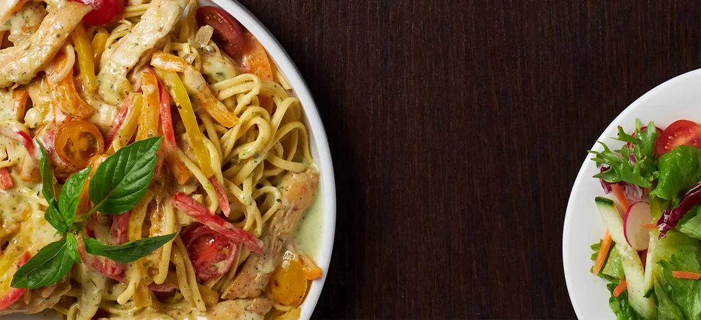 Creamy chicken pasta with bell peppers, tomatoes, and a fresh salad.