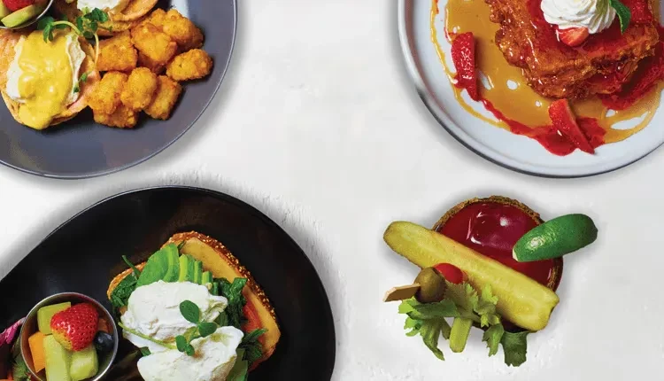 Four diverse brunch plates and a garnished Bloody Mary, flat lay.