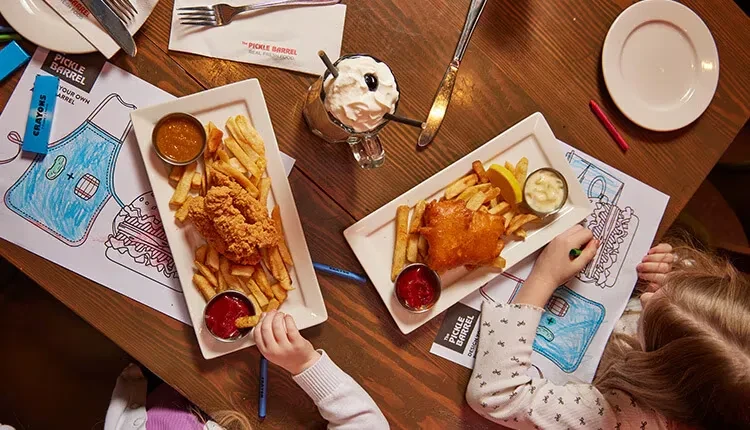 Restaurant table with children's chicken, fish, fries, milkshake, and coloring activities.