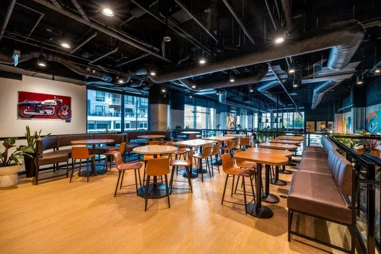 Modern empty restaurant with industrial black ceiling and brown leather seating.