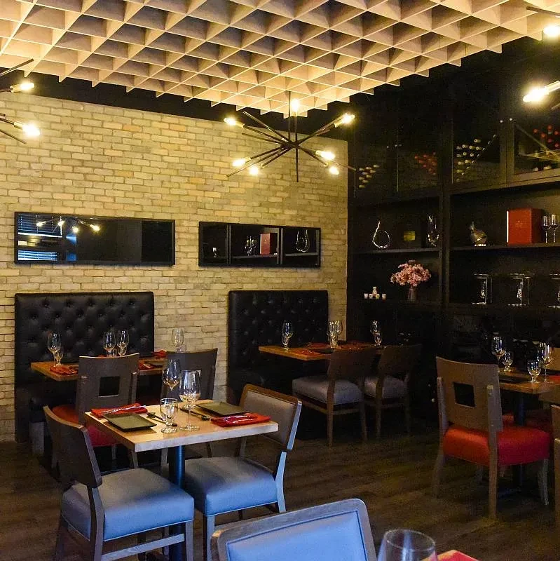 Modern restaurant with set tables, brick walls, wood ceiling, and chandeliers.
