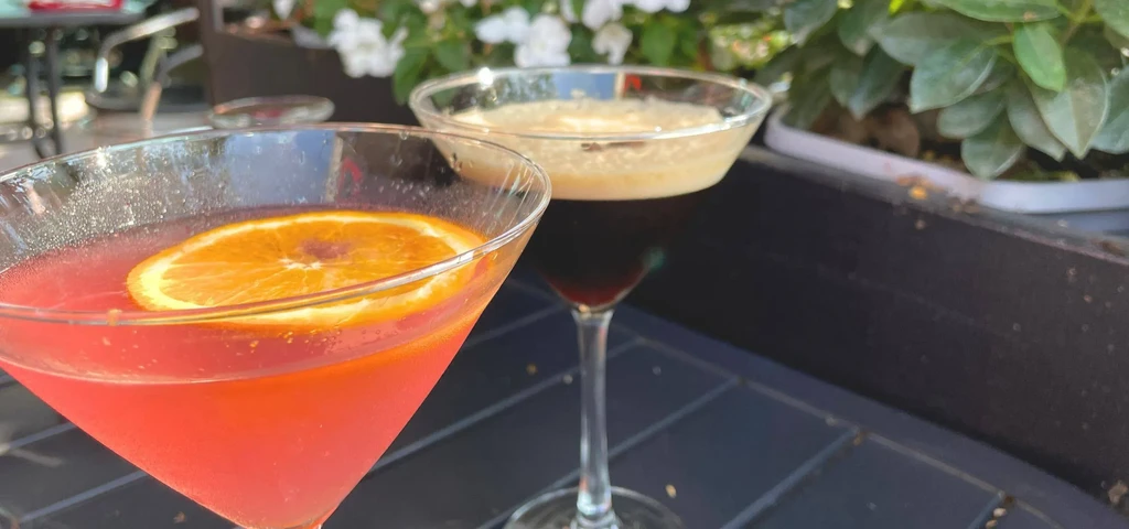 Pink martini with orange and brown martini on outdoor table.