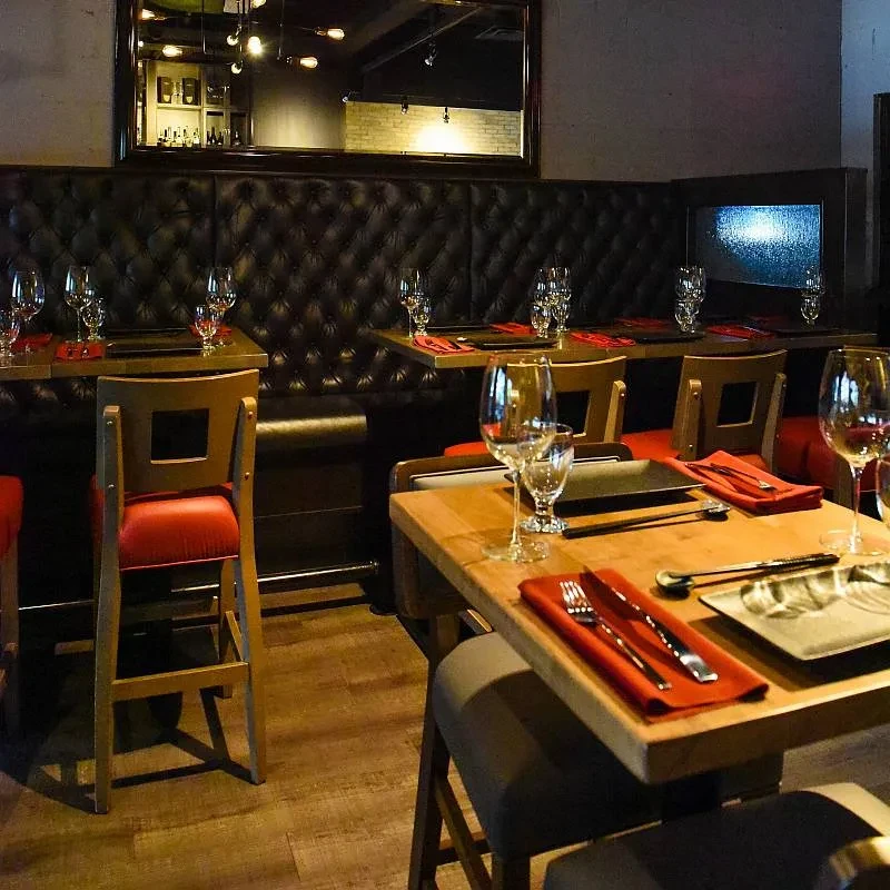 Warmly lit modern restaurant interior with elegant booths and set tables.