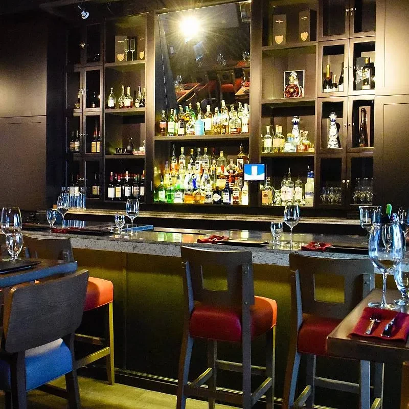 Upscale bar with stocked shelves, polished counter, and red bar stools.