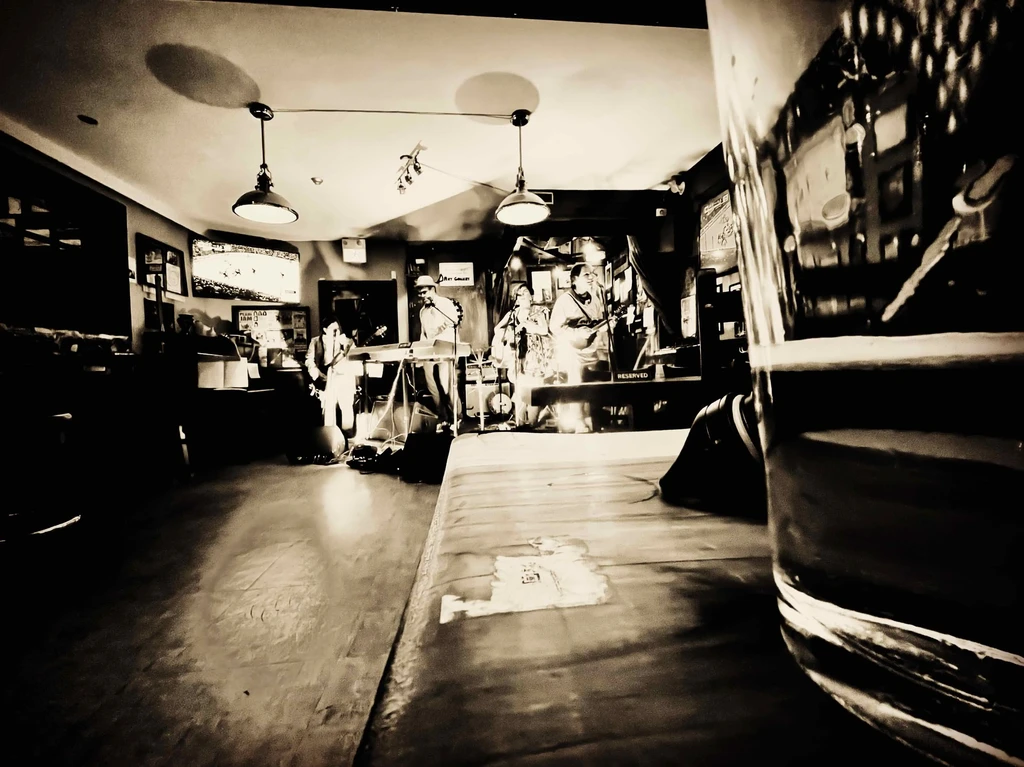 Black and white photo: band performs on dimly lit stage.