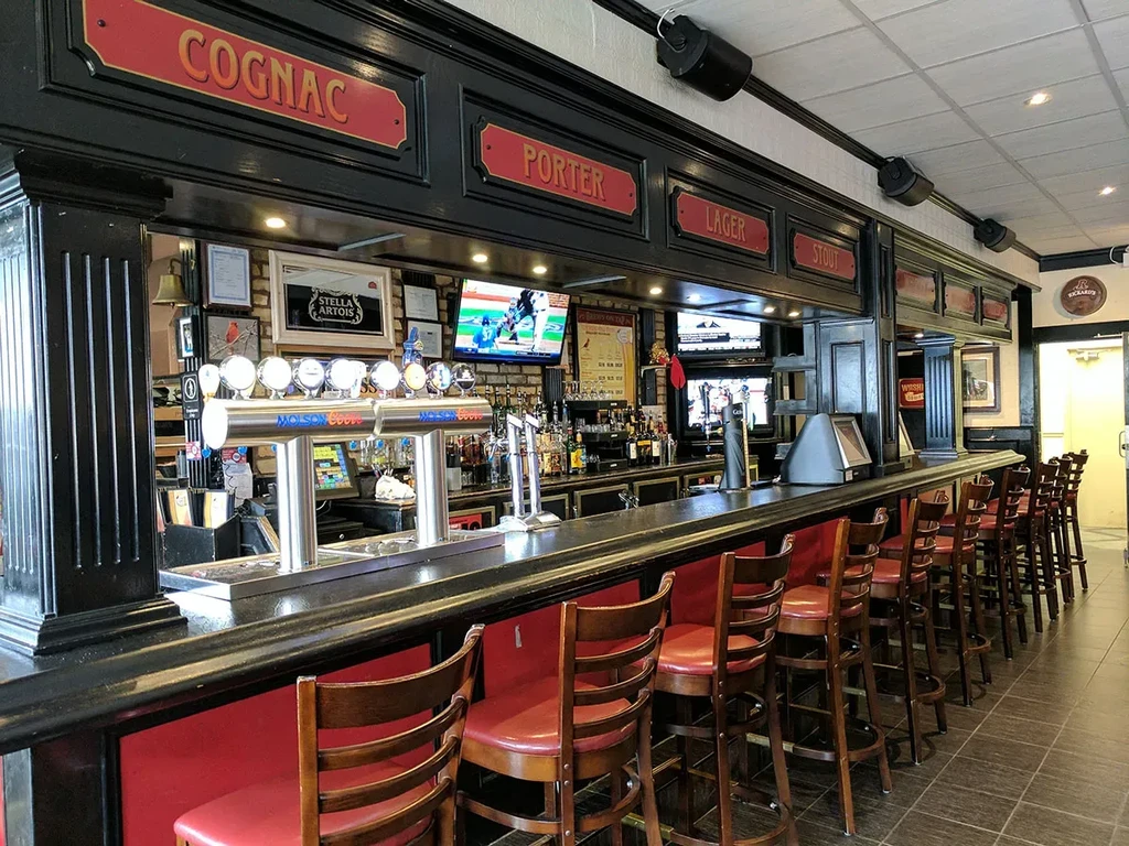 Empty traditional dark wood bar with beer taps and sports on TV.