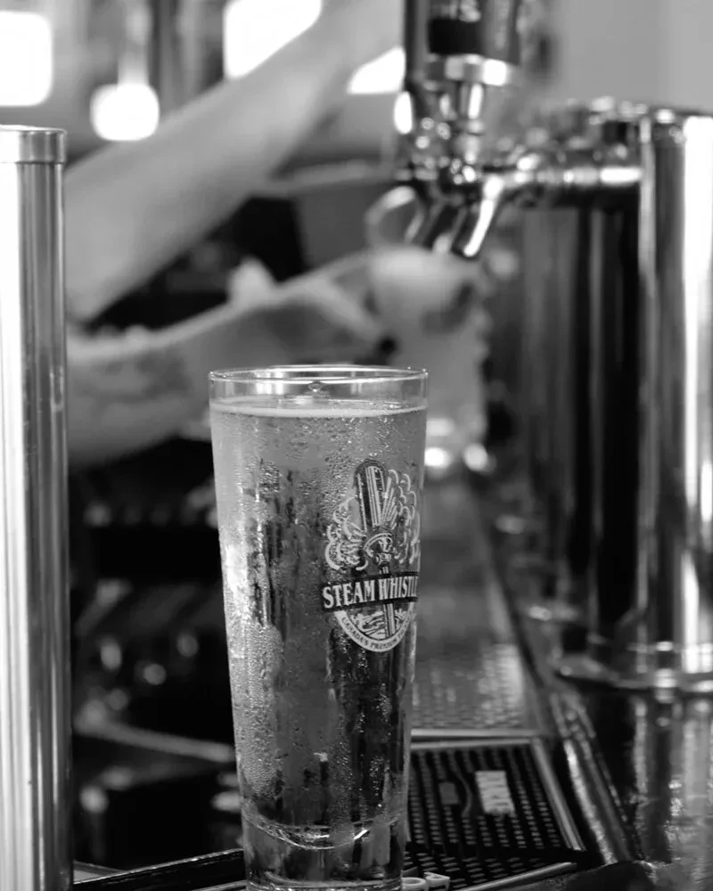 Black and white Steam Whistle beer glass with condensation on a bar.