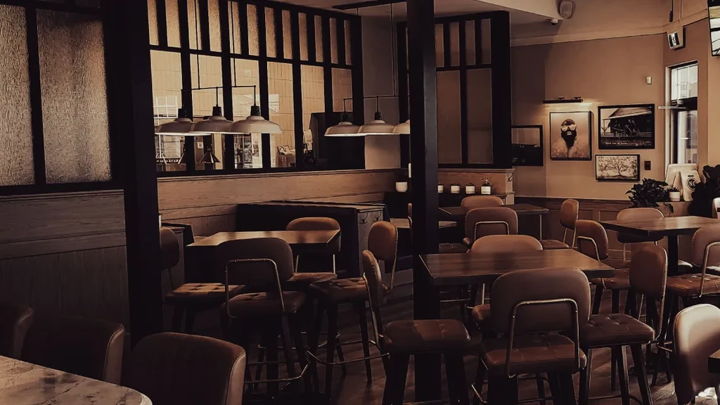 Empty, cozy restaurant interior with wooden tables, leatherette chairs, industrial lamps.