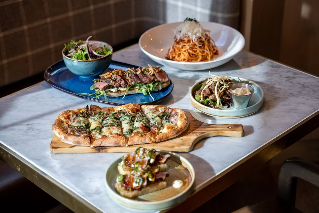 Assortment of well-plated dishes on a marble table in a restaurant setting.