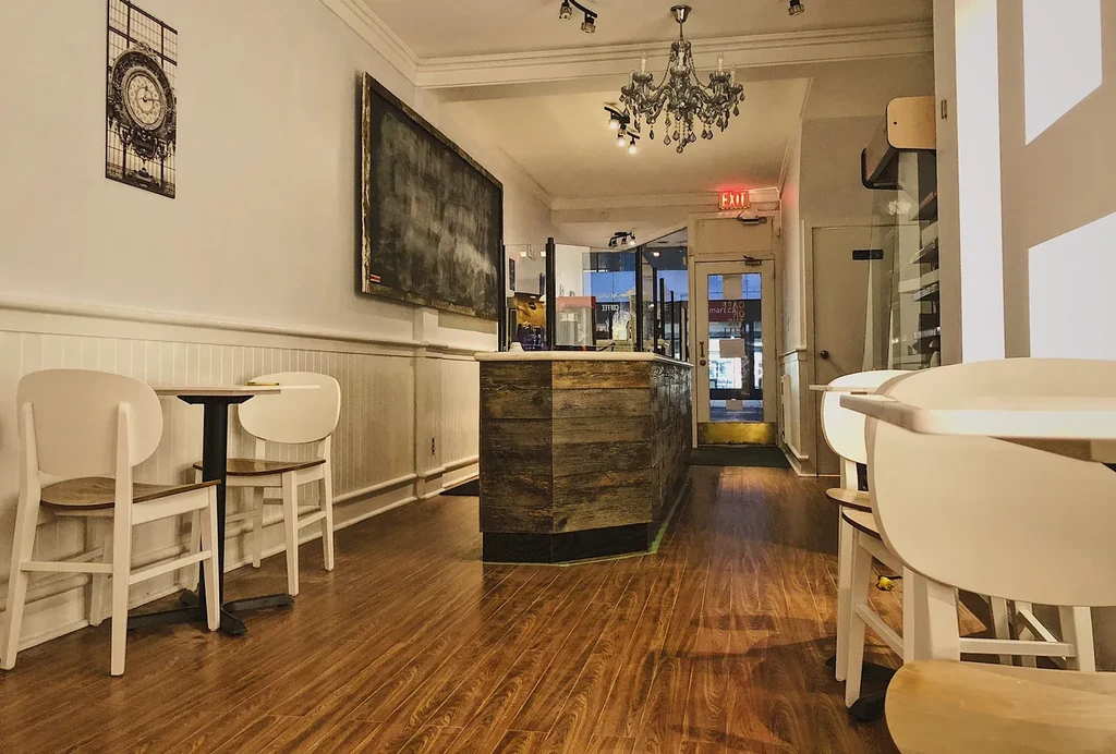 Empty small restaurant interior with tables, a rustic counter, and an exit.