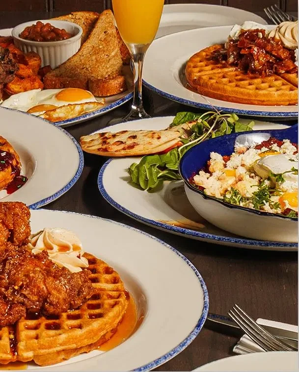 A spread of various breakfast and brunch dishes on a dark tabletop.