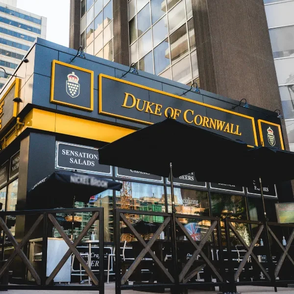 Urban Duke of Cornwall pub, black and yellow facade, shaded patio.