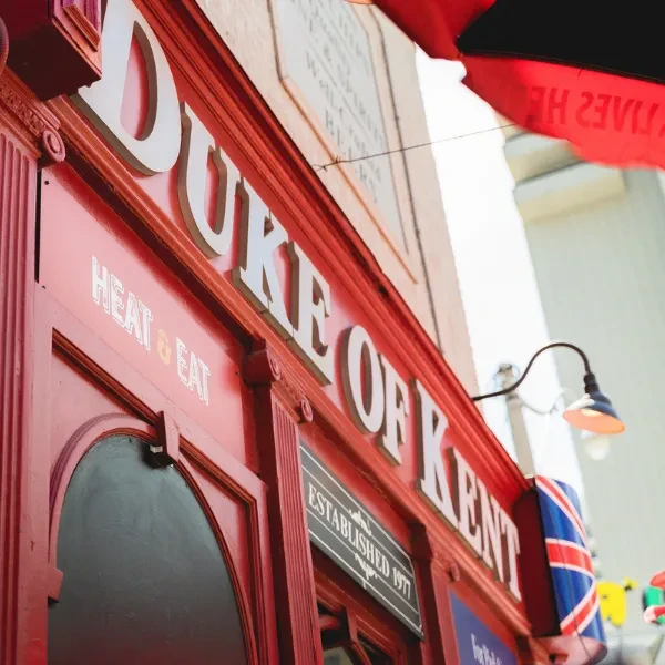 Red Duke of Kent pub exterior with glowing sconce light.