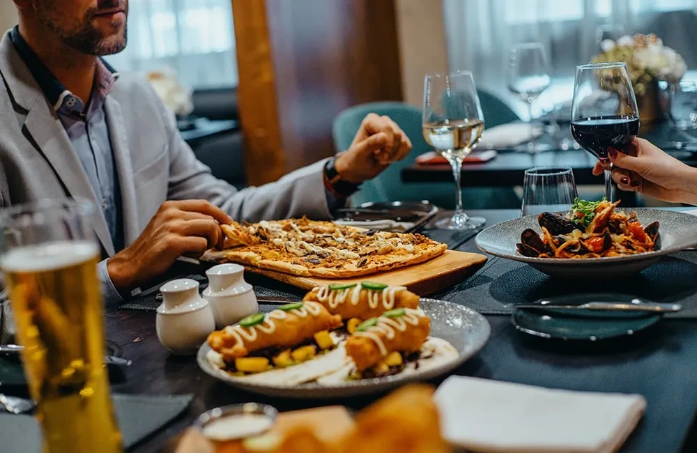 Upscale restaurant table with pizza, pasta, tacos, beer, and wines.
