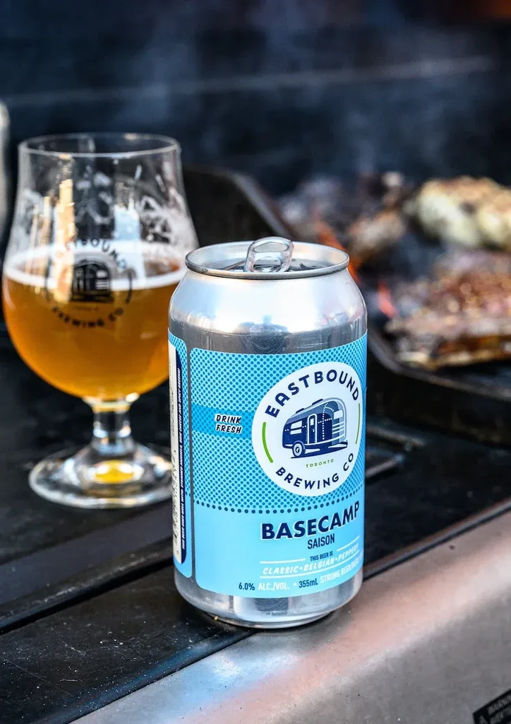 Eastbound Brewing Co. beer can, glass, and grill cooking food.