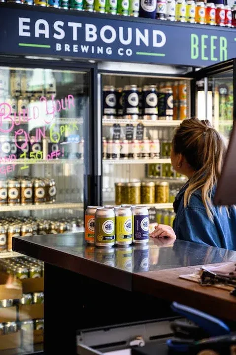 Customer views refrigerators filled with Eastbound Brewing Co. beer cans.