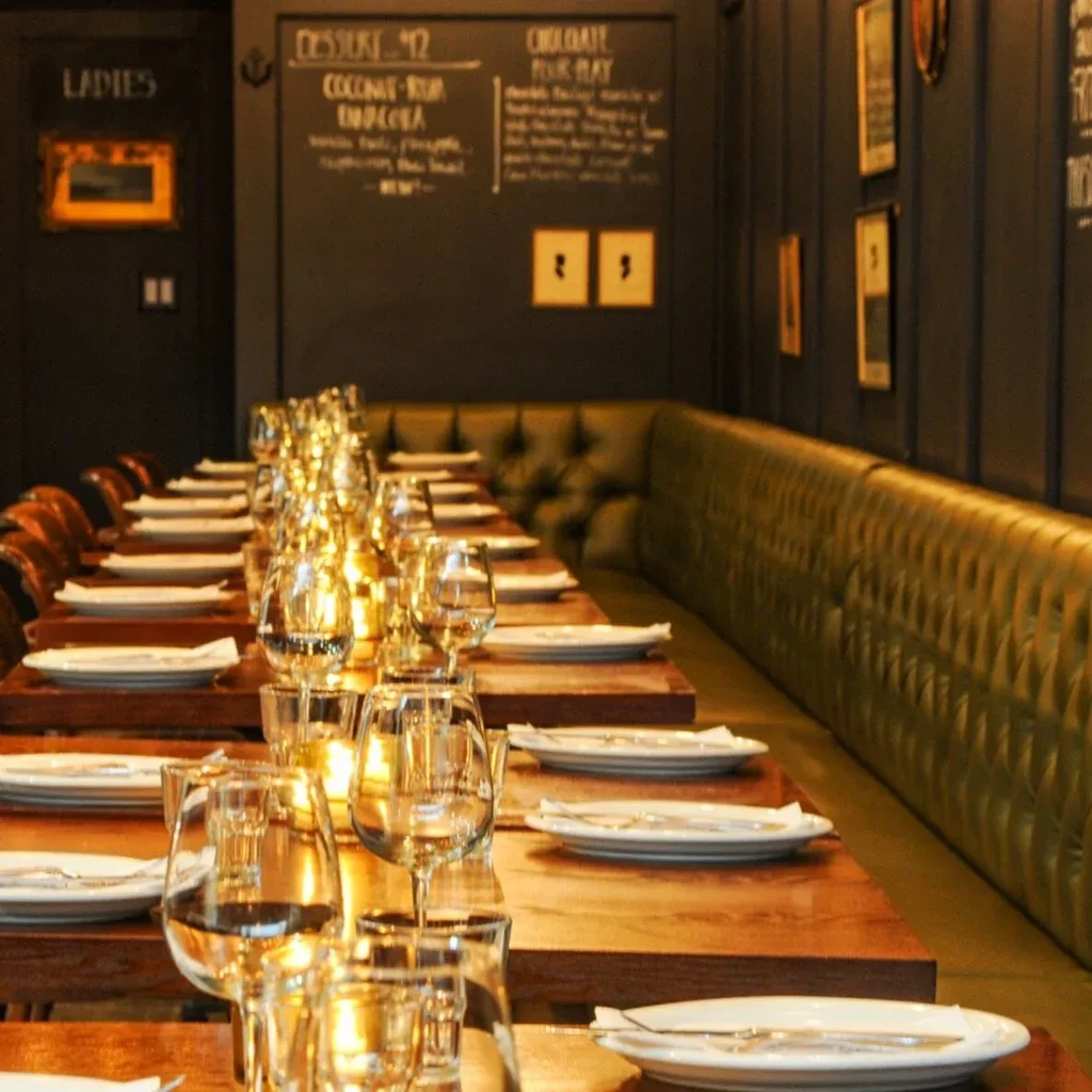 Warmly lit restaurant with set wooden table, green banquettes, and dessert menu.
