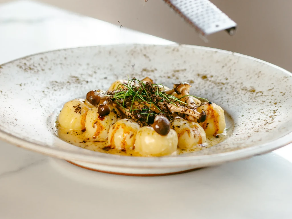 Golden gnocchi with mushrooms, herbs, and freshly grated truffle.