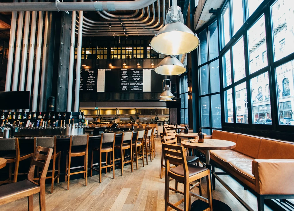 Spacious modern industrial-chic restaurant interior with bar, menu, and seating.