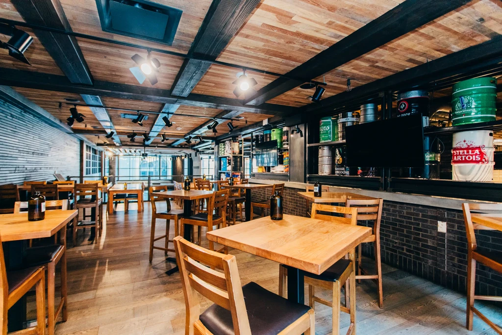 Empty modern rustic restaurant interior with exposed beams and bar.
