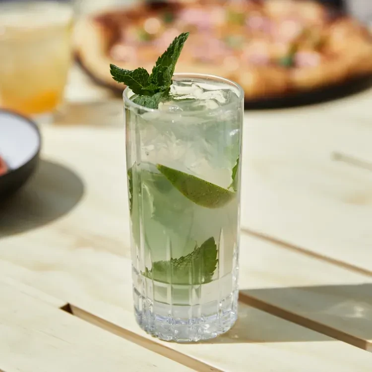 Light green drink with mint and lime on a wooden table.