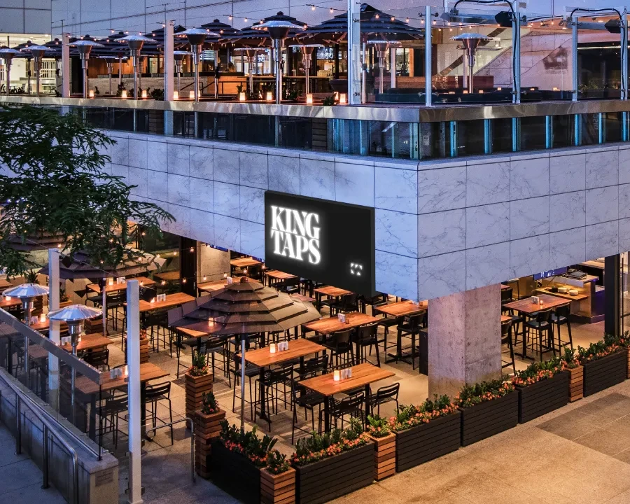 KING TAPS: modern restaurant with two brightly lit outdoor patios at night.