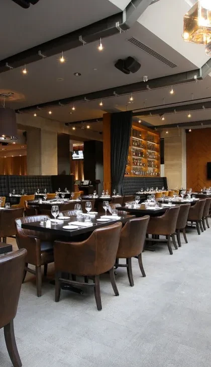 Sophisticated empty restaurant dining area, finely set tables, well-stocked bar.