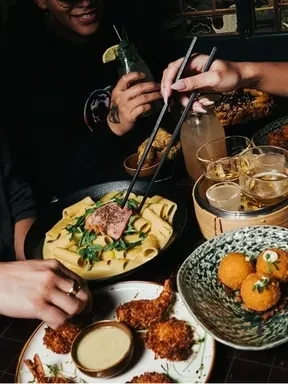 Shared pasta, shrimp, and cocktails on a dimly lit restaurant table.
