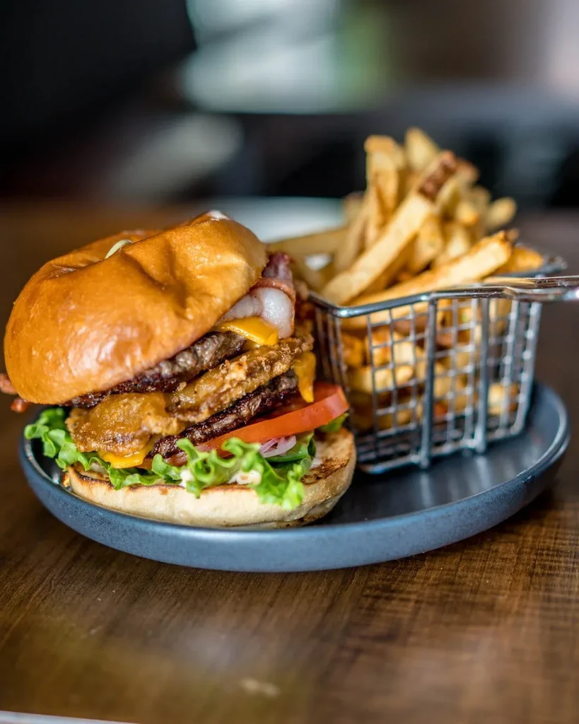 Double cheeseburger with bacon, lettuce, tomato, and a side of fries.