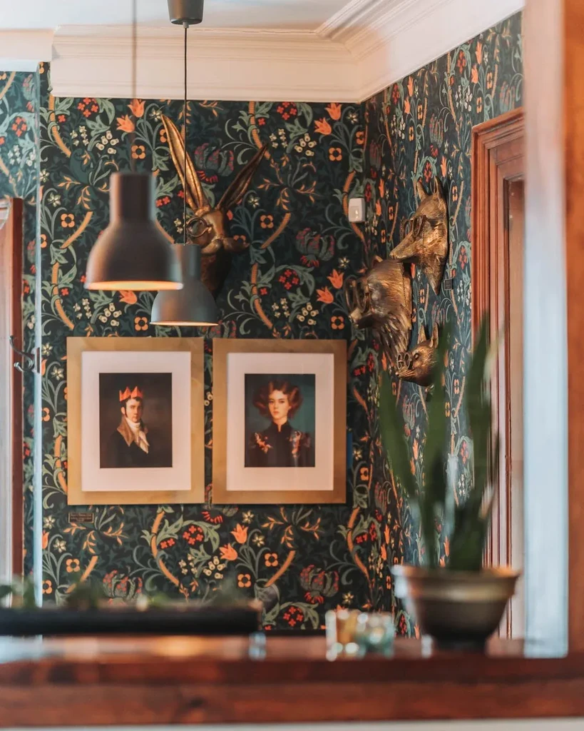 Intricate floral wallpaper, golden animal busts with glasses, and classical portraits.
