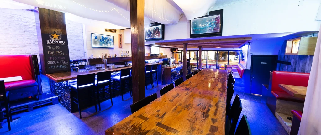 Modern bar interior with strong blue lighting and a communal table.