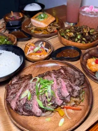 Overhead view of steak, salmon, rice, and vegetables on a wooden table.